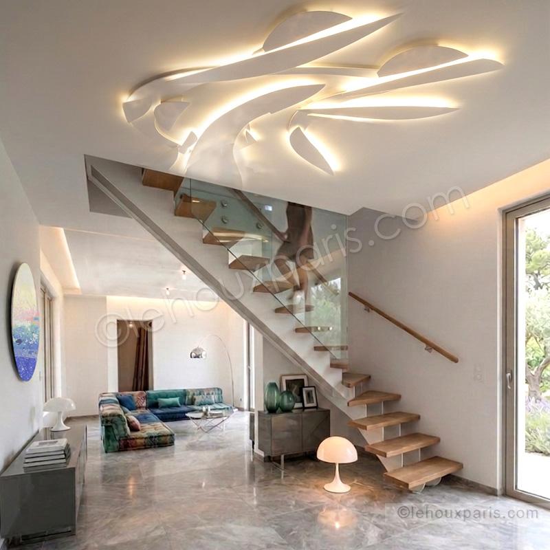 Suspension sculpturale Lehoux Paris, rampe d'escalier contemporaine et mobilier Roche Bobois dans un salon de duplex avec baie vitrée vue tour Eiffel.